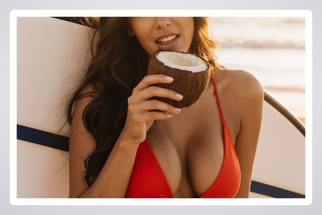 Curvy latina drinking coconut on beach