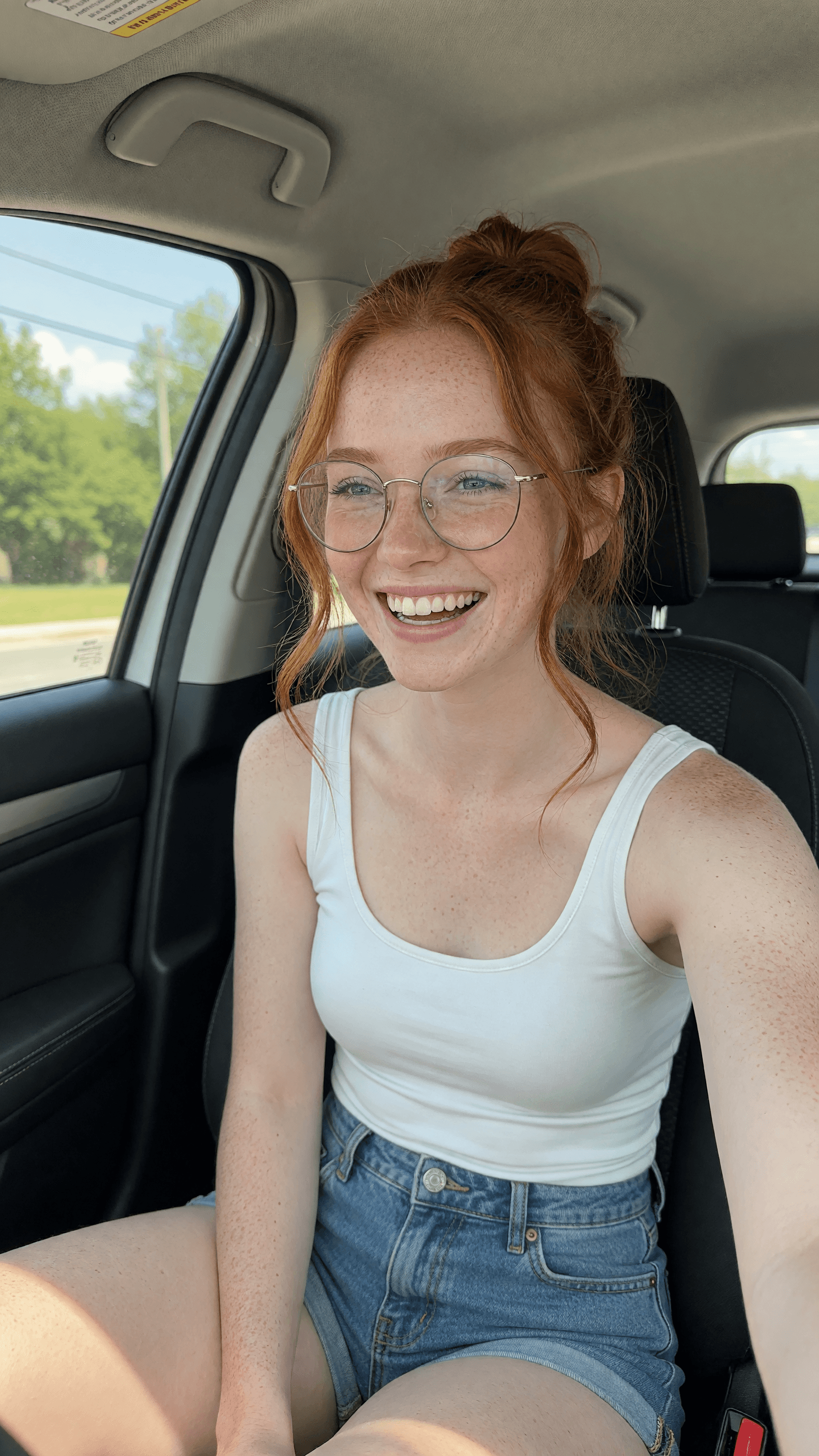 Redhead with glasses laughing in car passenger seat