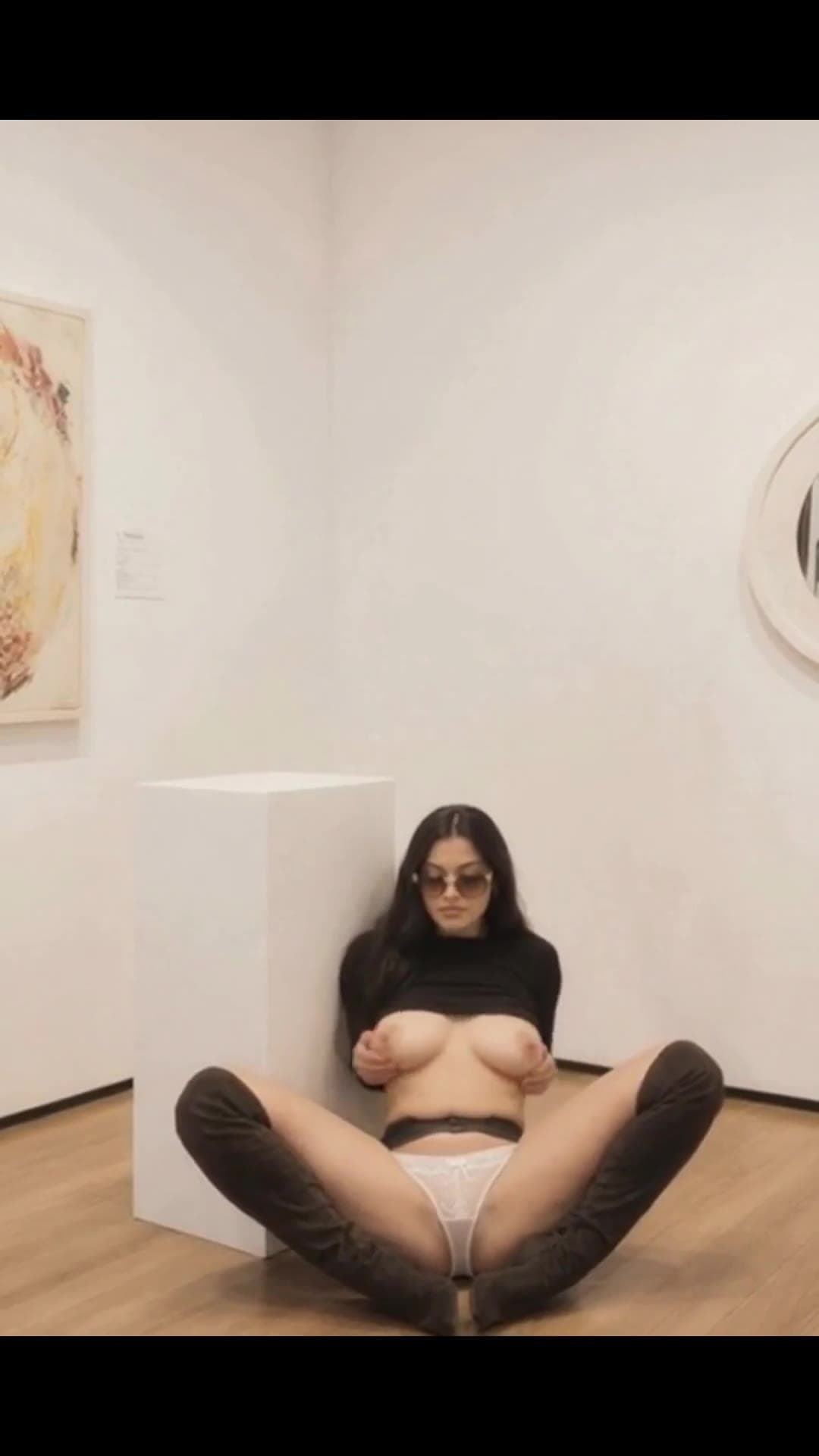 Legs spread wide in art gallery topless