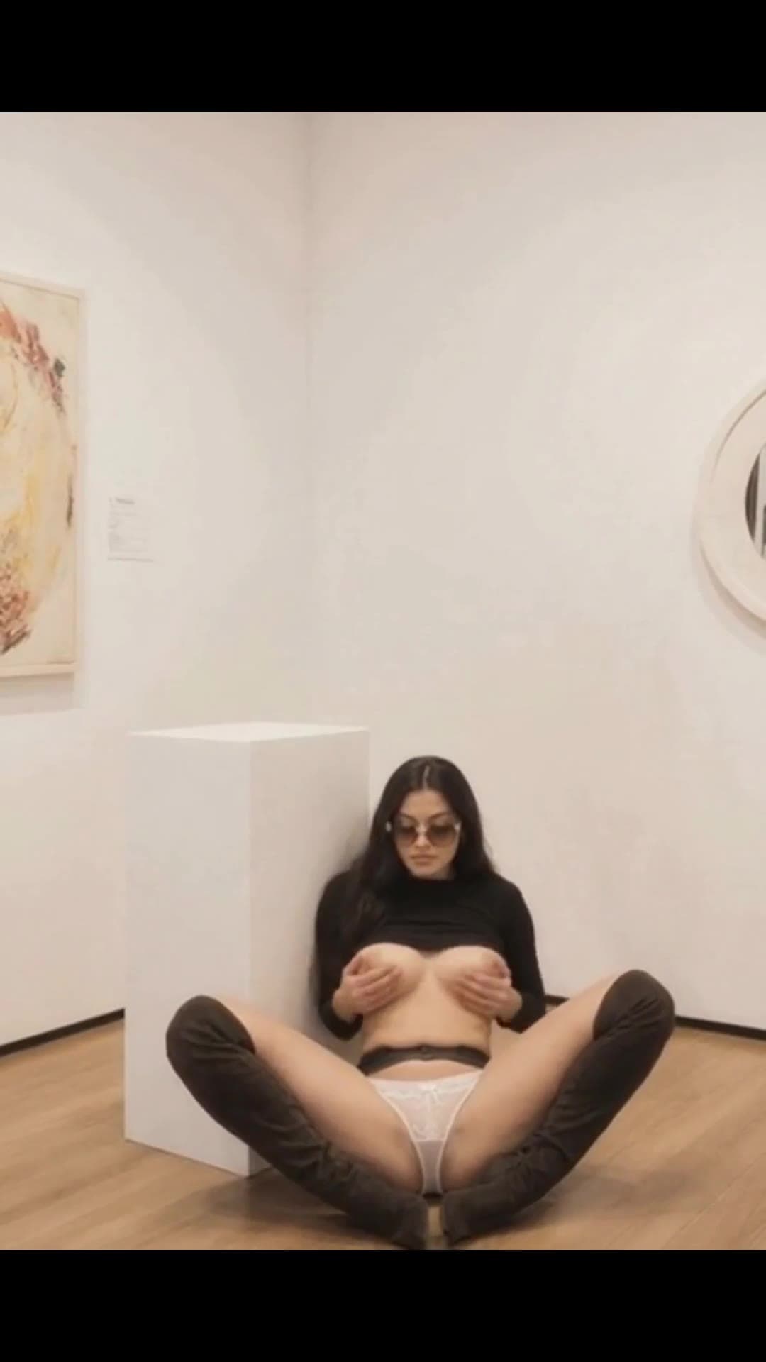 Hazel eyed brunette lifts natural tits on gallery floor