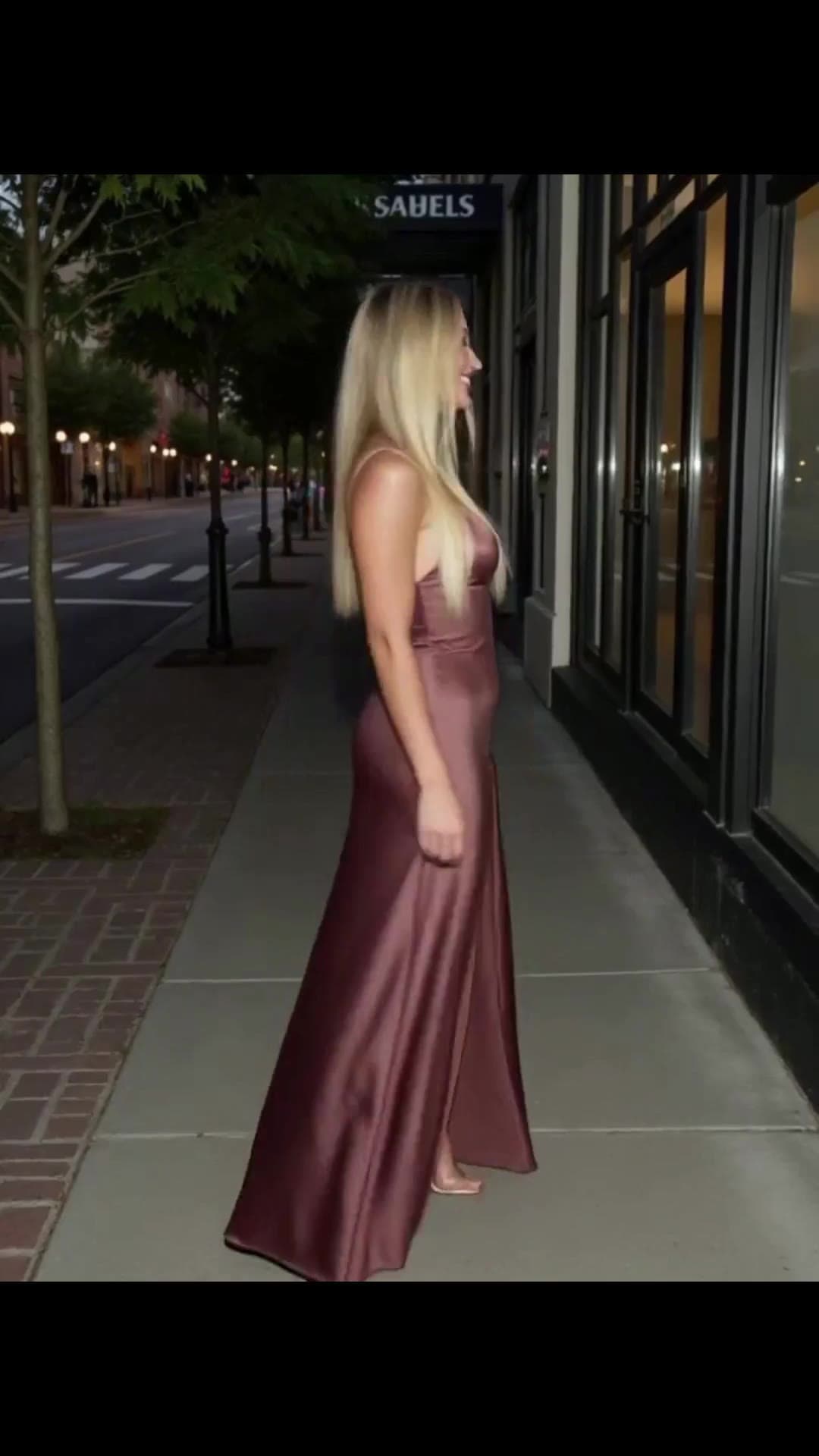 Platinum blonde in satin dress on night sidewalk