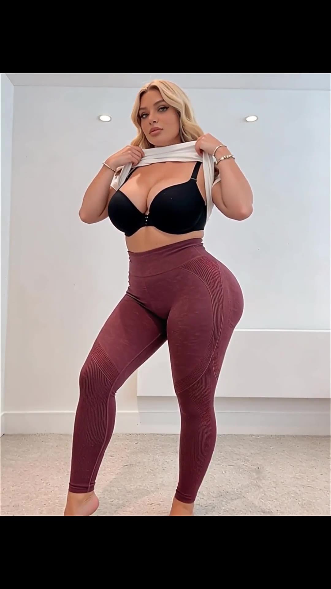 Latina in leggings lifts tank top facing camera
