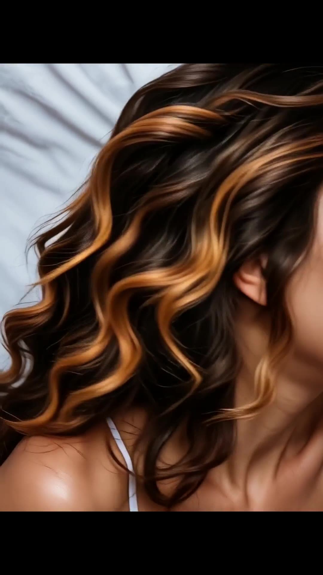 Wavy caramel hair on blue sheets