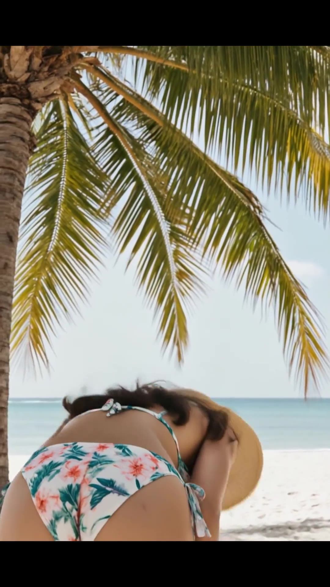 From behind floral bikini beach pose