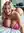 Elle in pink lingerie kneeling on a bed with a soft smile