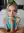 Brynn kneeling on the bed in turquoise sports bra